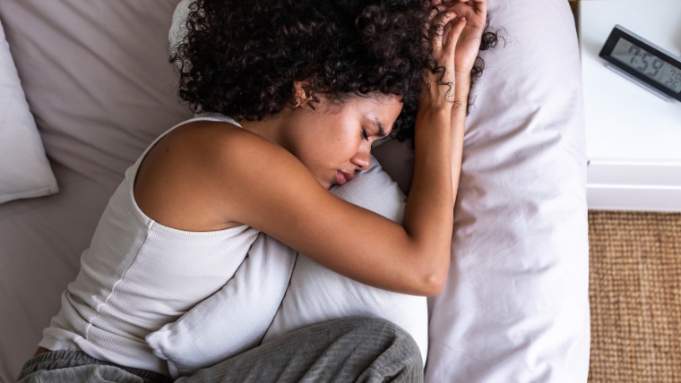 Black woman lying in bed uncomfortable and upset hugging her pillow | Beyond Depression 5 Common Illnesses Associated with Higher Risk in Patients with Depression | Mindful Health Solutions