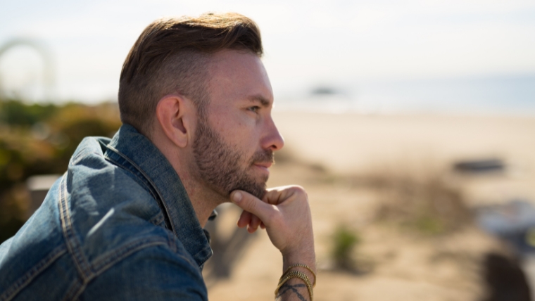 White man at the beach with his hand on his chin thinking | Bipolar Disorder and Bipolar Cycles: What you need to know | Mindful Health Solutions