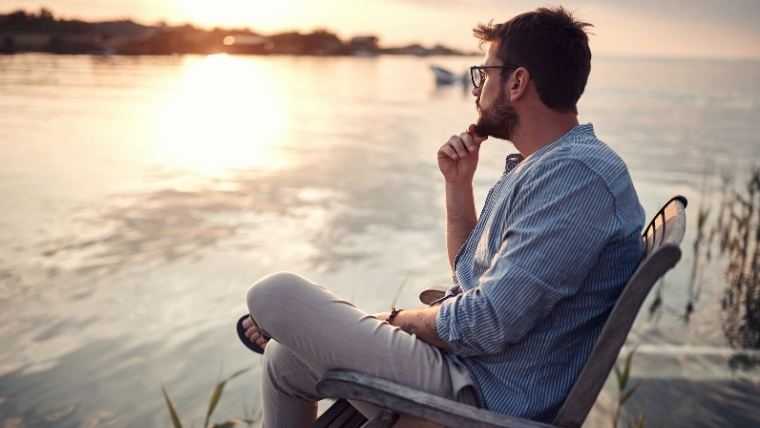 Man sitting in chair on a doc enjoying the sunset | Embrace These 7 Types of Rest | Mindful Health Solutions