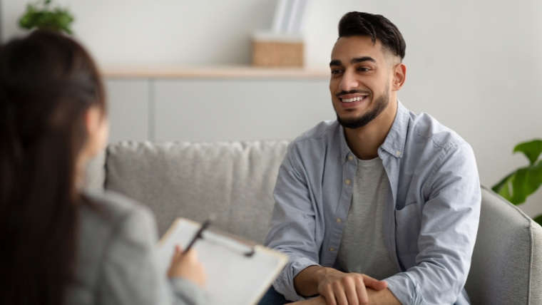 Man on couch in therapist office smiling at his therapist | Therapy Enhancement :10 Topics to Kickstart Meaningful Discussions | Mindful Health Solutions