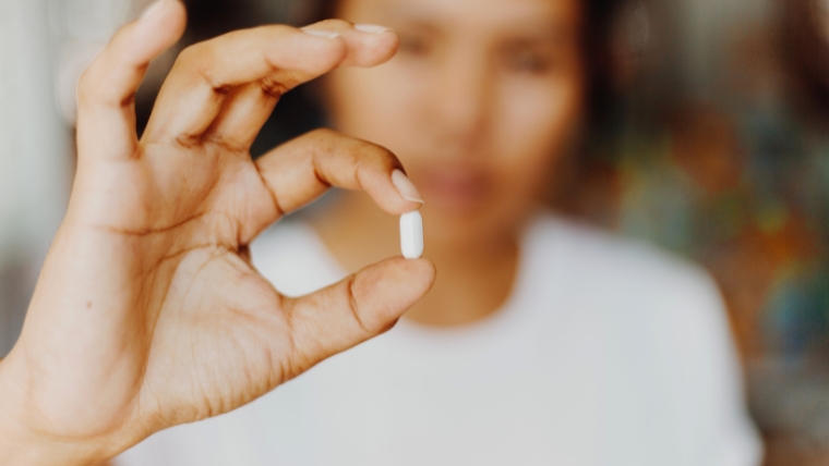 Person holding pill up close to the camera | The Influence of Antidepressants on the Brain: A Comprehensive Guide | Mindful Health Solutions