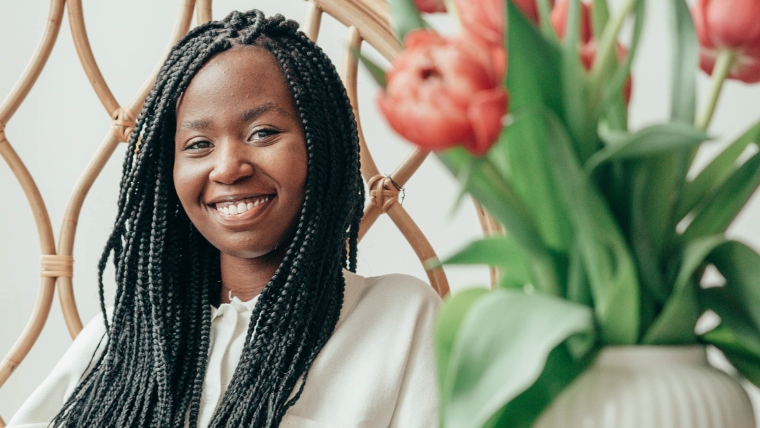 A black woman sitting and smiling at the camera behind a vase of red tulips | Ketamine Infusion Therapy How It Works, What to Expect, and Who Can Benefit | Mindful Health Solutions