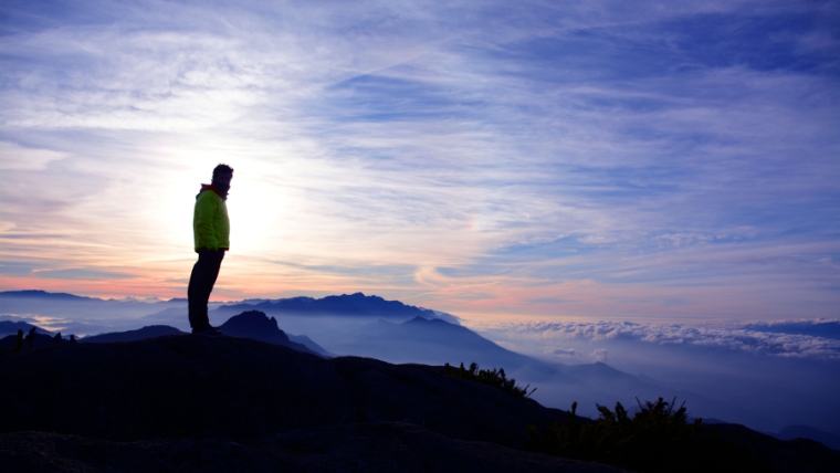 Man standing on top of a mountain, overlooking a landscape of mountaintops and clouds | Ketamine for Mental Health A Miracle Drug or Hype | Mindful Health Solutions