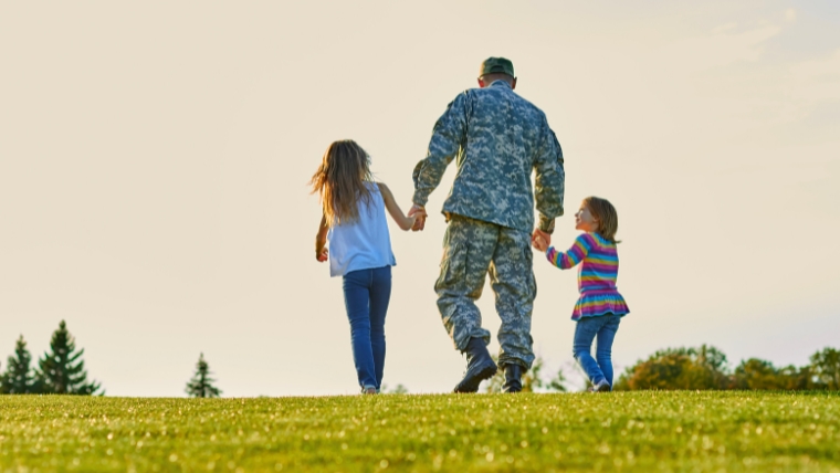 Veteran father in the middle of two daughters, holding their hands | Supporting Our Heroes Comprehensive Mental Health Care for Veterans | Mindful Health Solutions