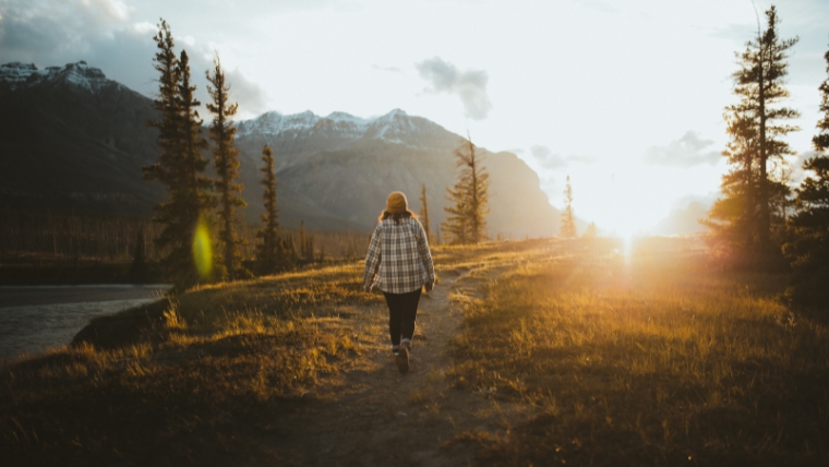 Woman walking in nature towards the sun | Set These 10 New Year's Resolutions to Help Overcome Depression | Mindful Health Solutions