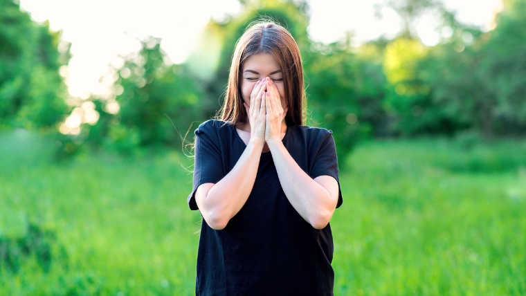 Young woman standing in field smiling with hands over her mouth | Did You Know 9 Shocking Facts About Esketamine Therapy | Mindful Health Solutions