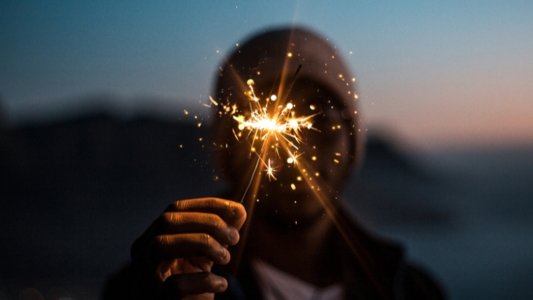 Man holding a sparkler in front of the camera at dusk | Start the New Year with a Positive Mindset How to Overcome Anxiety and Stay Calm | Mindful Health Solutions