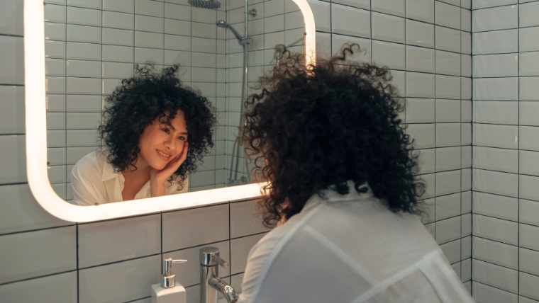 A woman looking at herself lovingly in a mirror | What Are Affirmations and Do They Actually Help? What To Know | Mindful Health Solutions