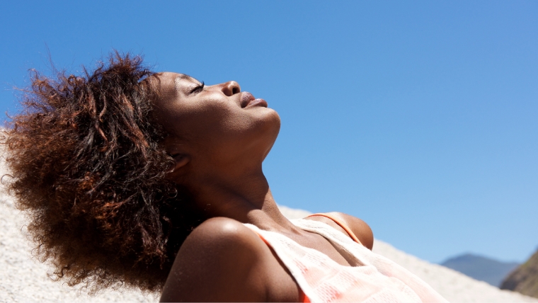 A woman laying on the beach soaking up the sun | Coping with Stress and Depression 20 Strategies for Feeling Better | Mindful Health Solutions