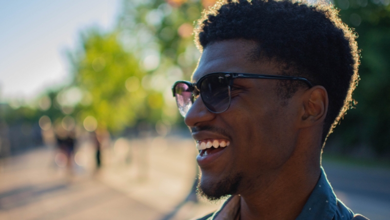 A man in sunglasses standing outside with a large smile on his face | Pain-Free Promise What You Need to Know About TMS Therapy | Mindful Health Solutions